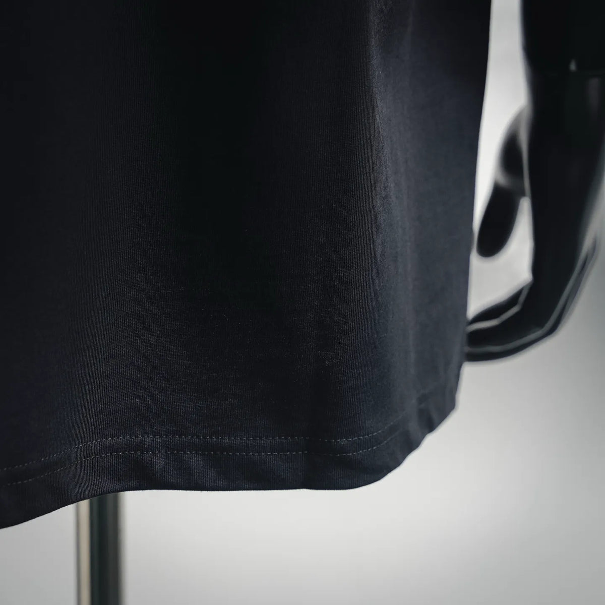 Dark T-shirt fabric close-up with stitched hem edge