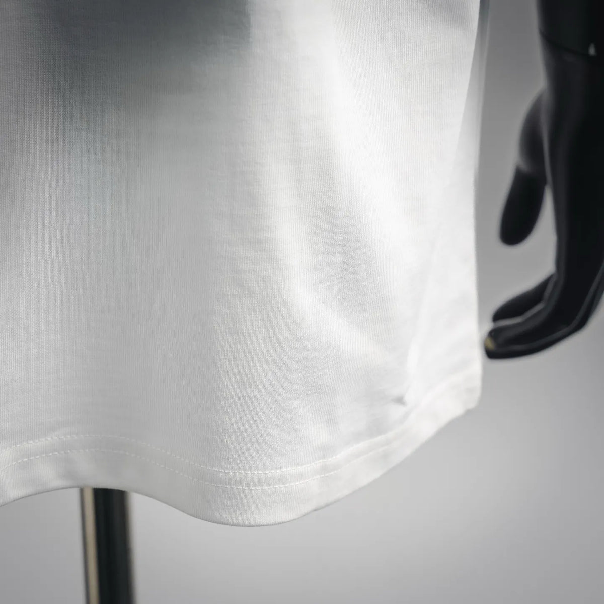 White T-shirt fabric close-up with stitched hem and curved side seam.