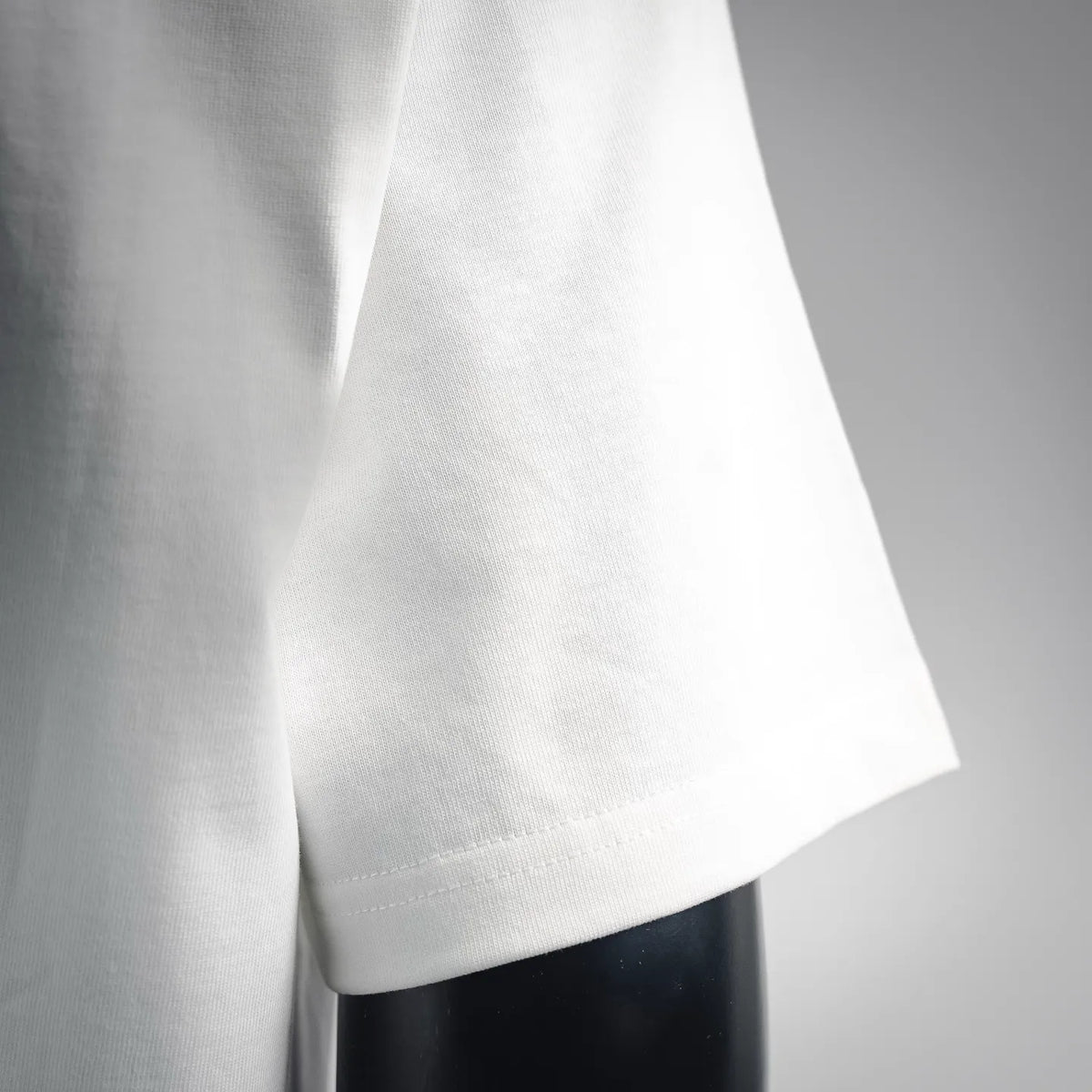 White T-shirt sleeve and side hem with visible stitching and clean finish.