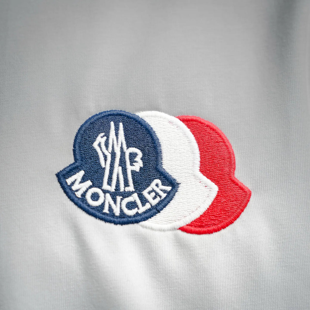 Moncler logo patch on white crewneck T-shirt, with blue and red accents