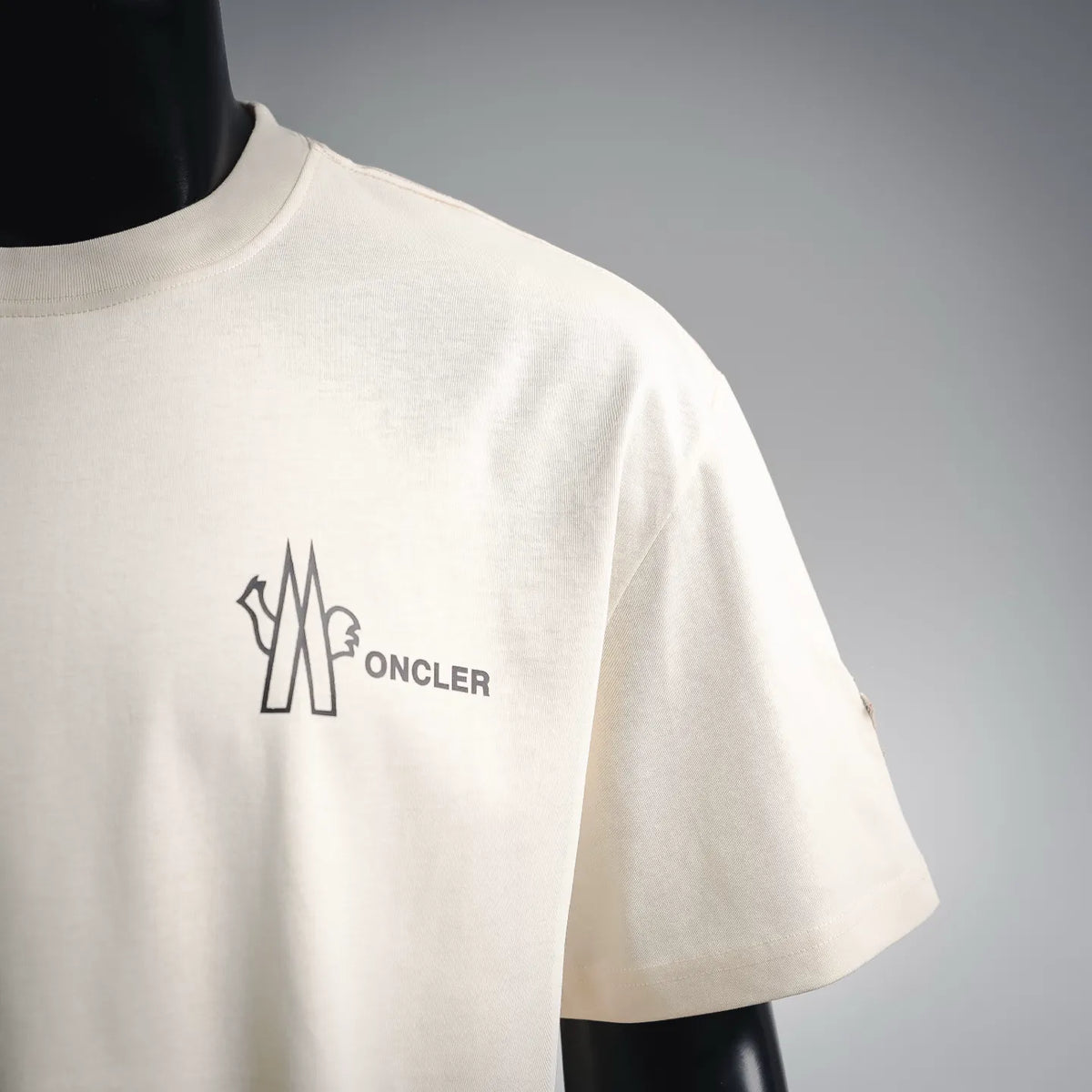 Cream short-sleeve T-shirt with large Moncler logo graphic on the chest.