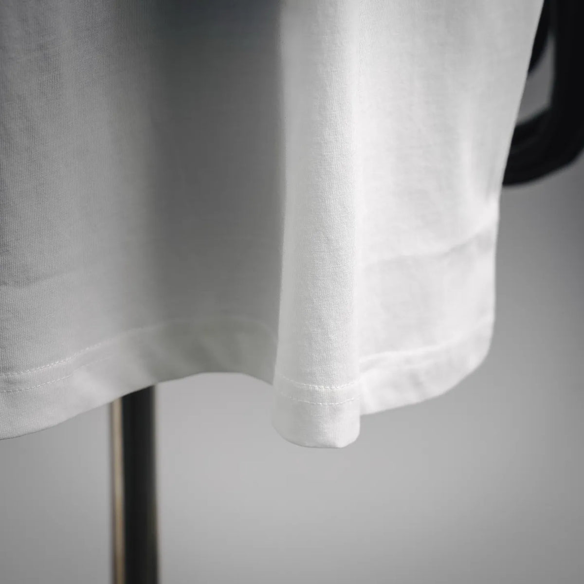 White short-sleeve T-shirt with curved hem and visible stitching.