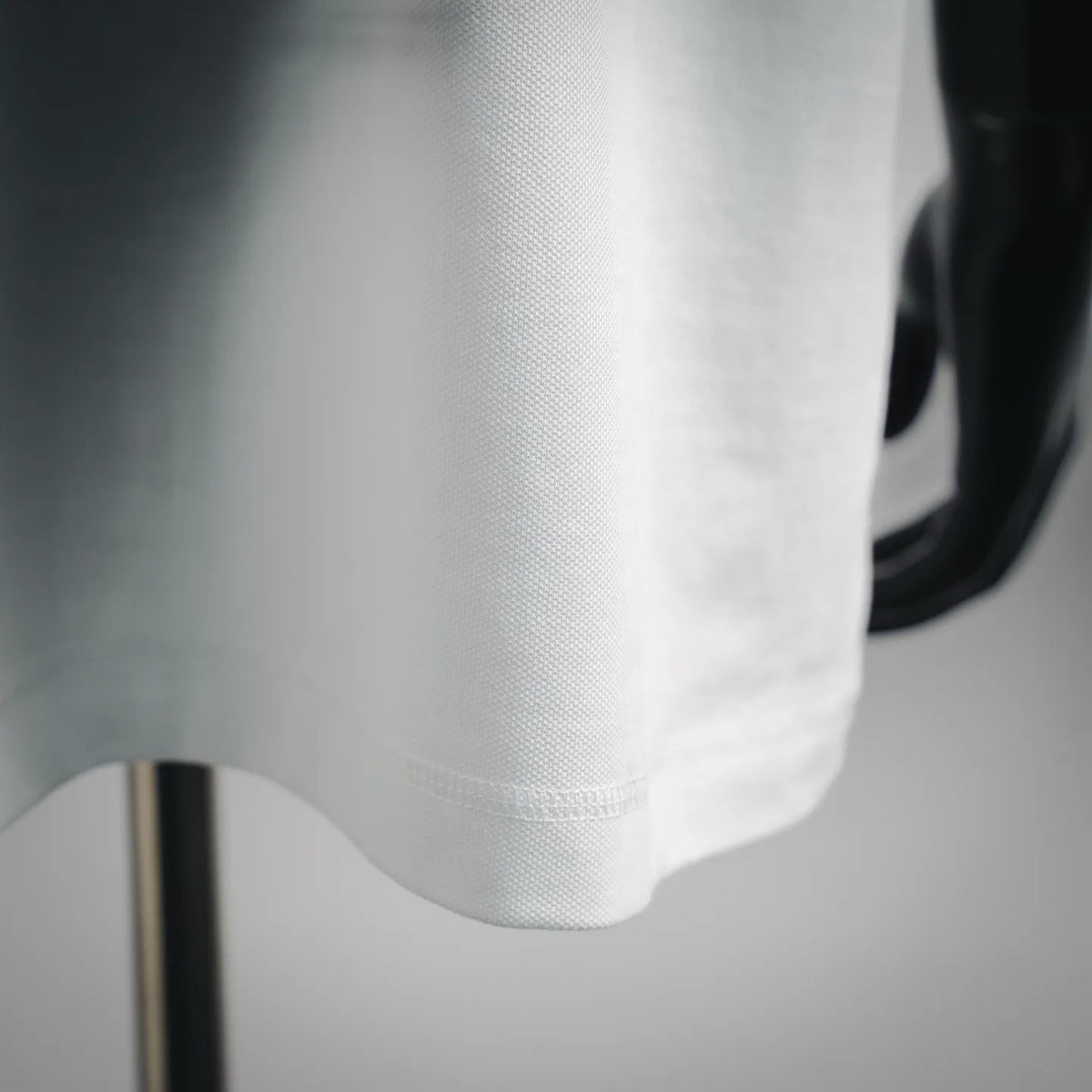 White polo shirt hem and fabric texture detail on short sleeve