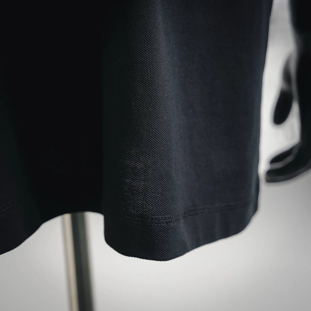 Dark black polo shirt fabric close-up with textured knit surface