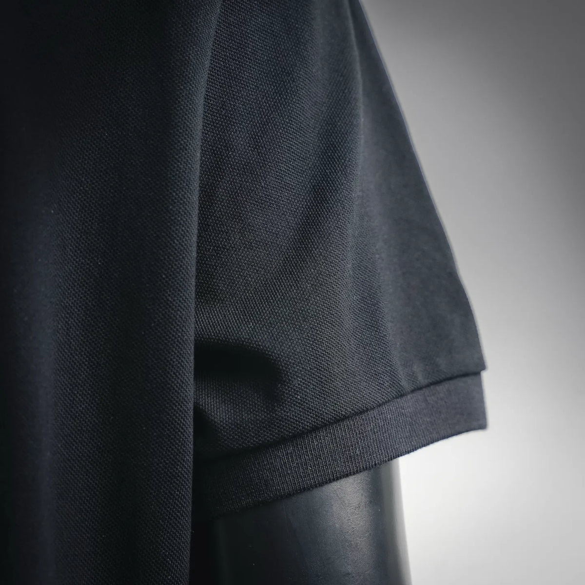 Dark black polo shirt sleeve hem with ribbed cuff and stitched seam