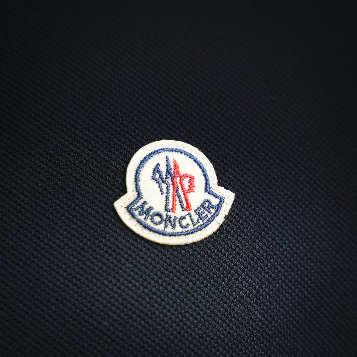 Moncler crest patch on dark polo shirt fabric