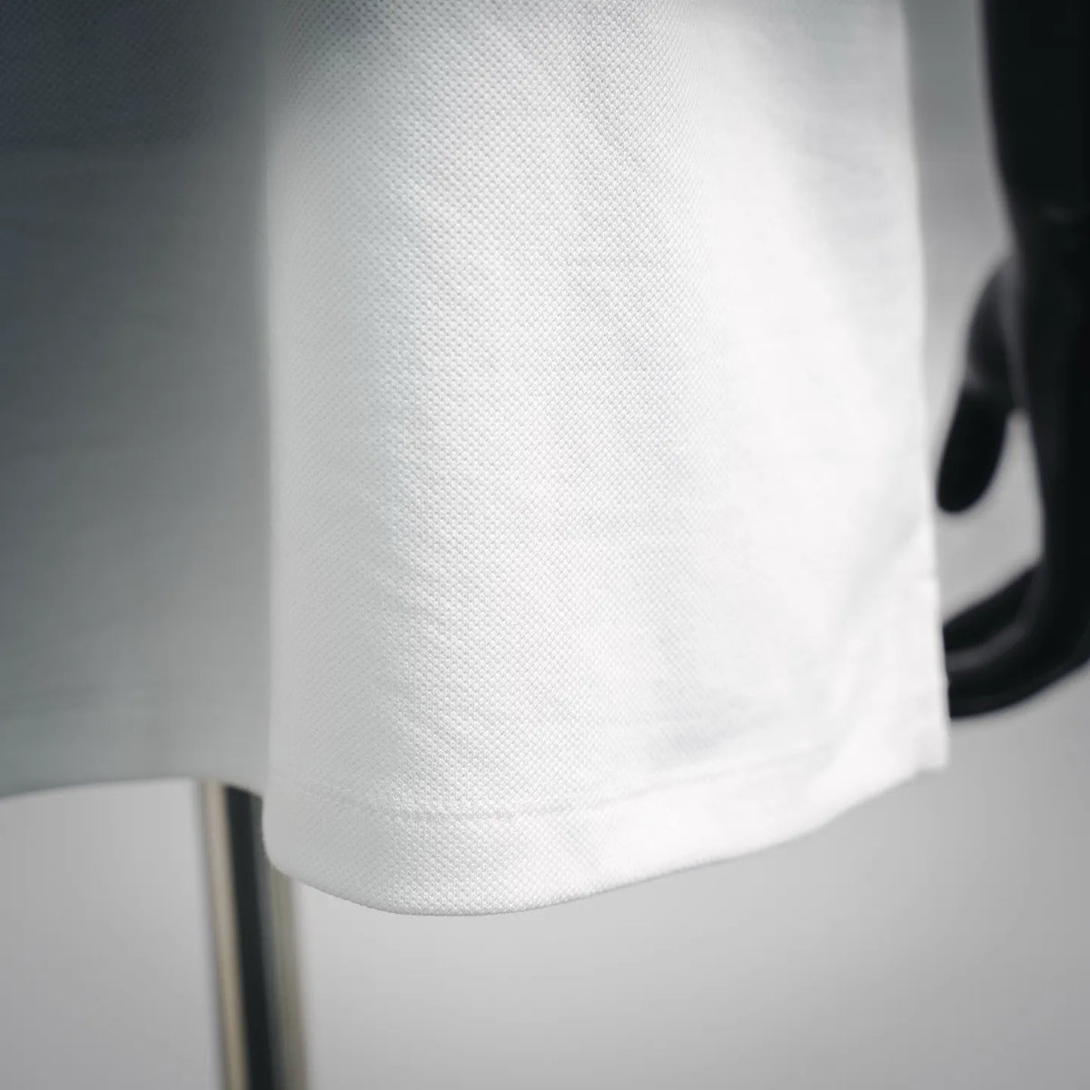 White pique polo fabric close-up with fine textured pattern