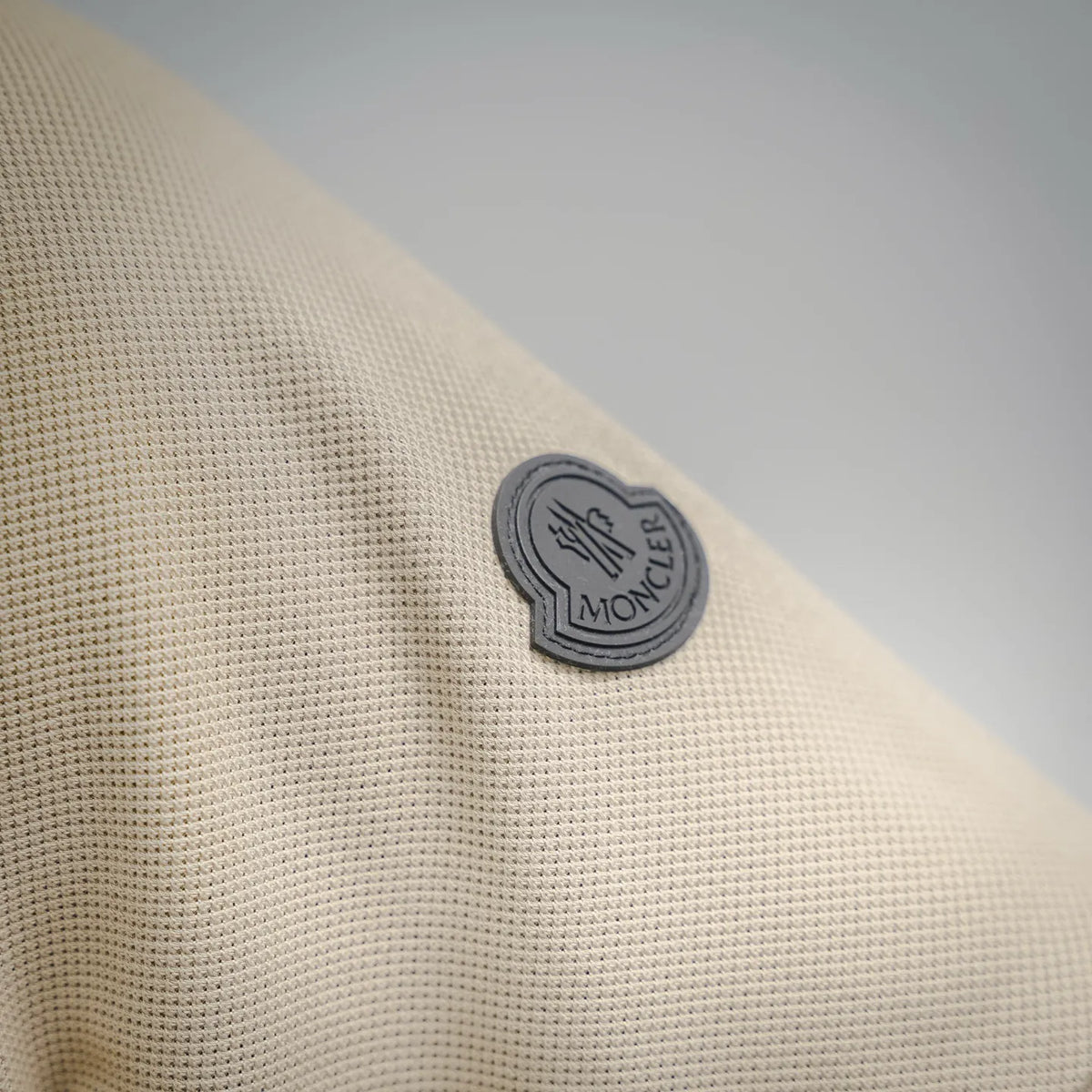 Circular Moncler logo patch on cream polo fabric