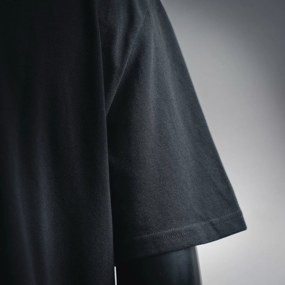 Close-up of black polo fabric and short sleeve hem seam