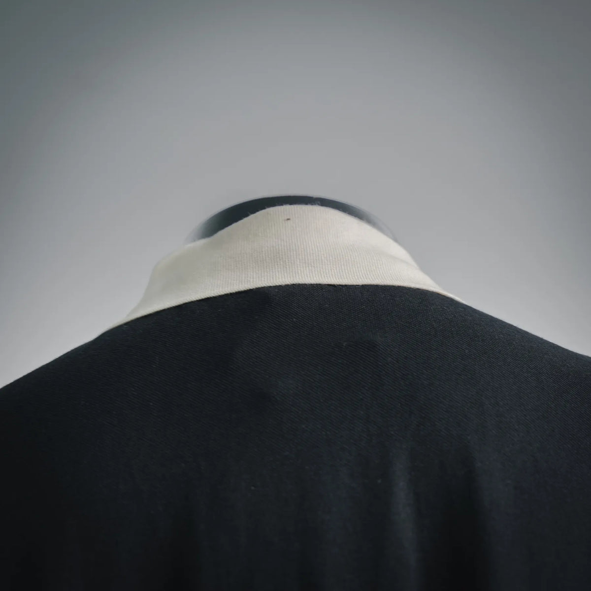 Close-up of black polo collar with white ribbed band