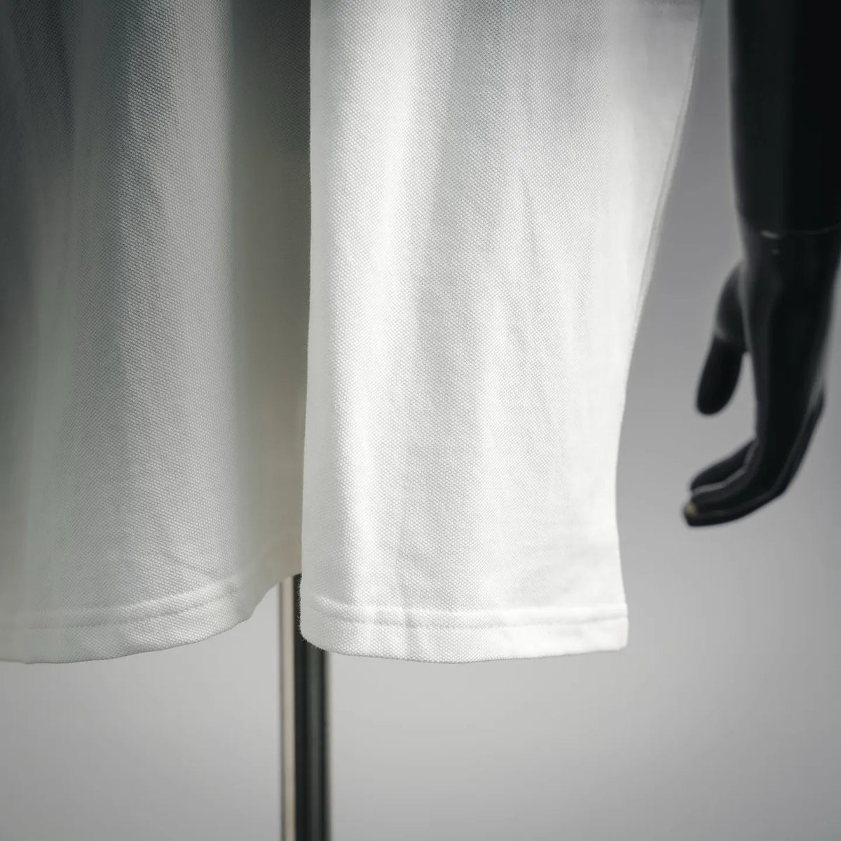 White polo shirt hem and side seam detail at the lower edge