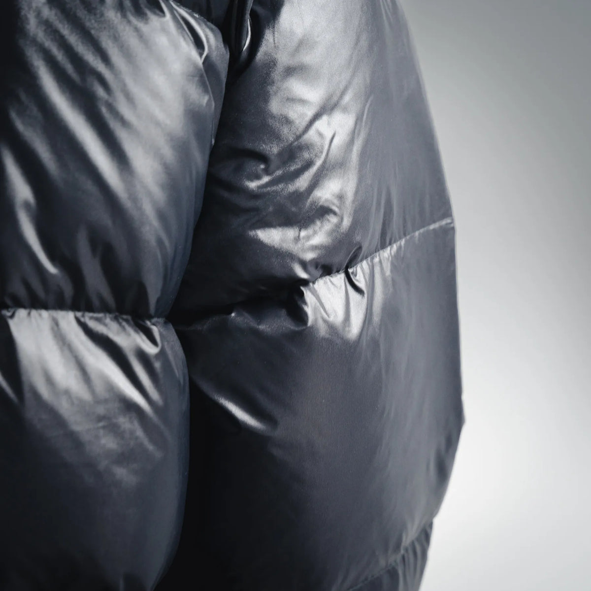 Moncler dark quilted puffer coat fabric close-up with padded panel stitching