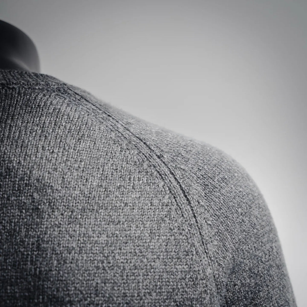 Gray knit sweater shoulder seam close-up with fine textured ribbing