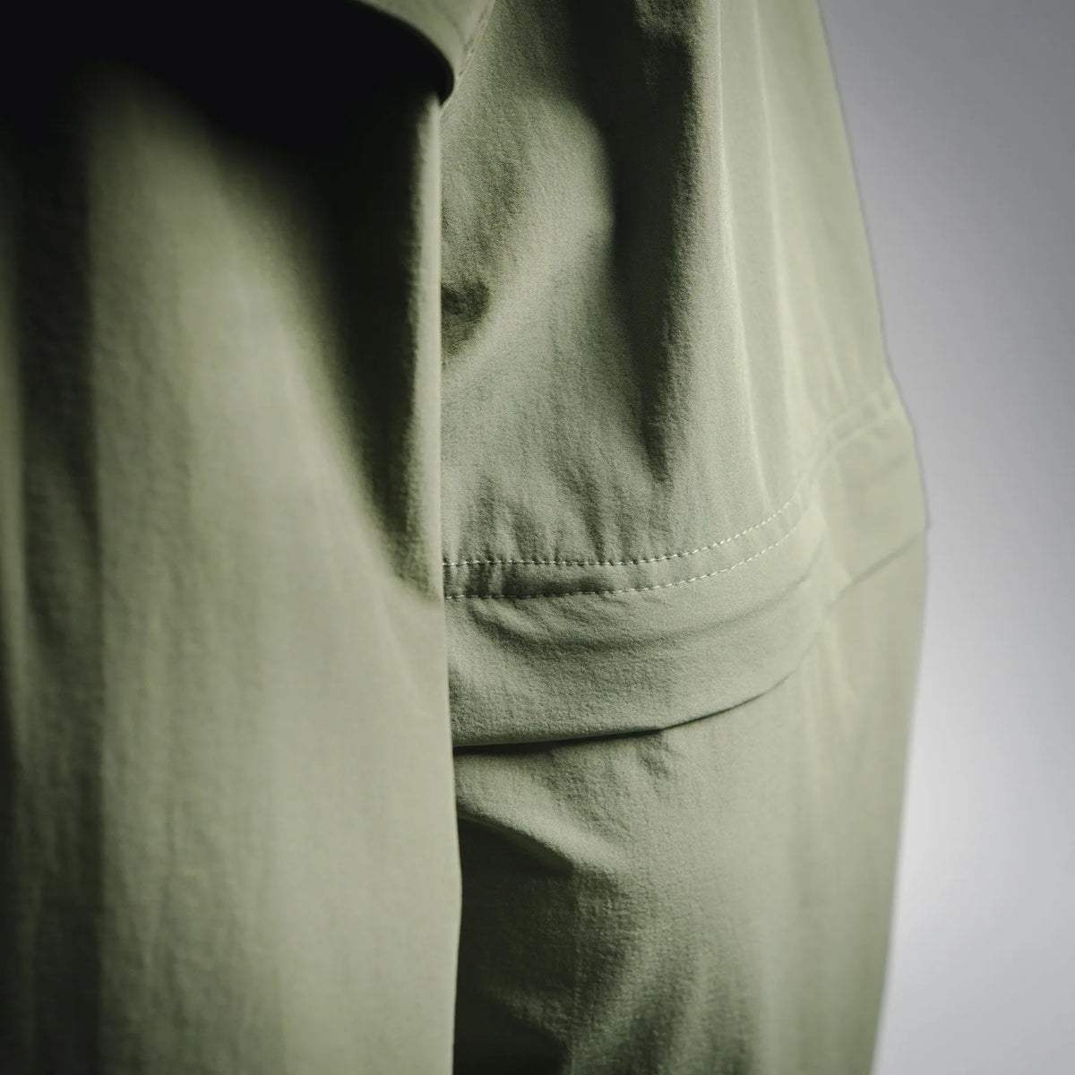Olive jacket panel detail with stitched hem and pocket seam