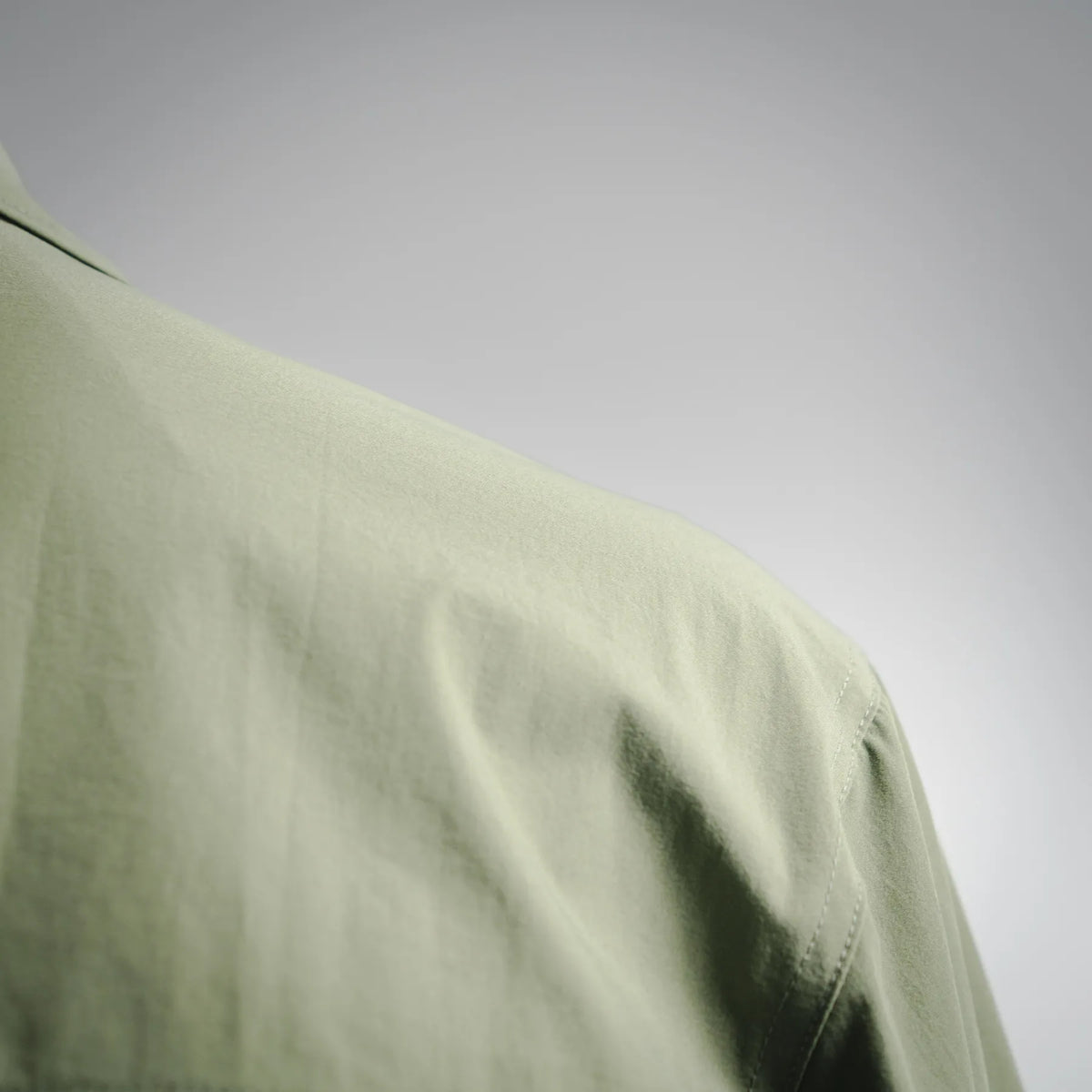 Olive jacket shoulder fabric close-up with curved seam
