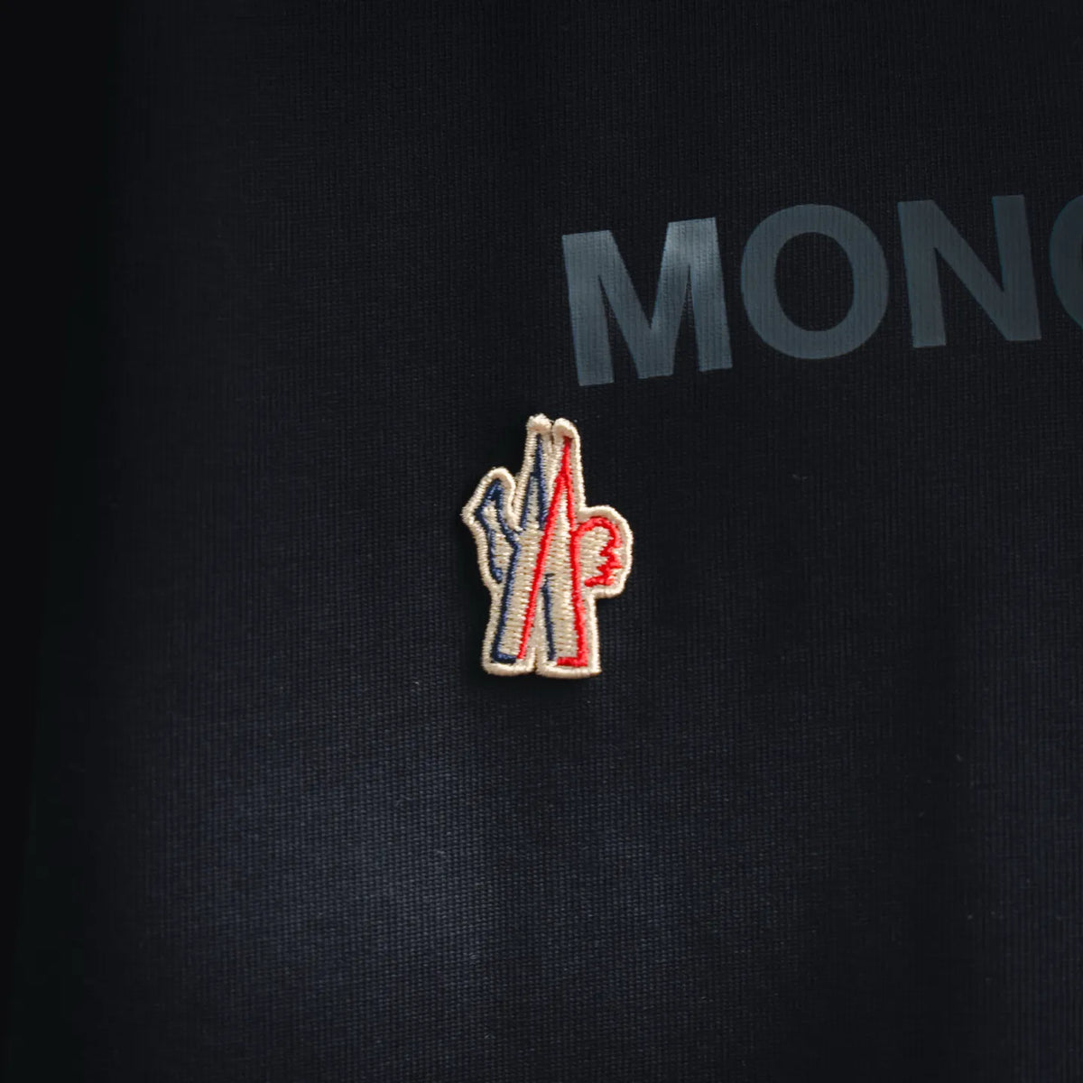 Embroidered Moncler Grenoble emblem on dark navy T-shirt chest