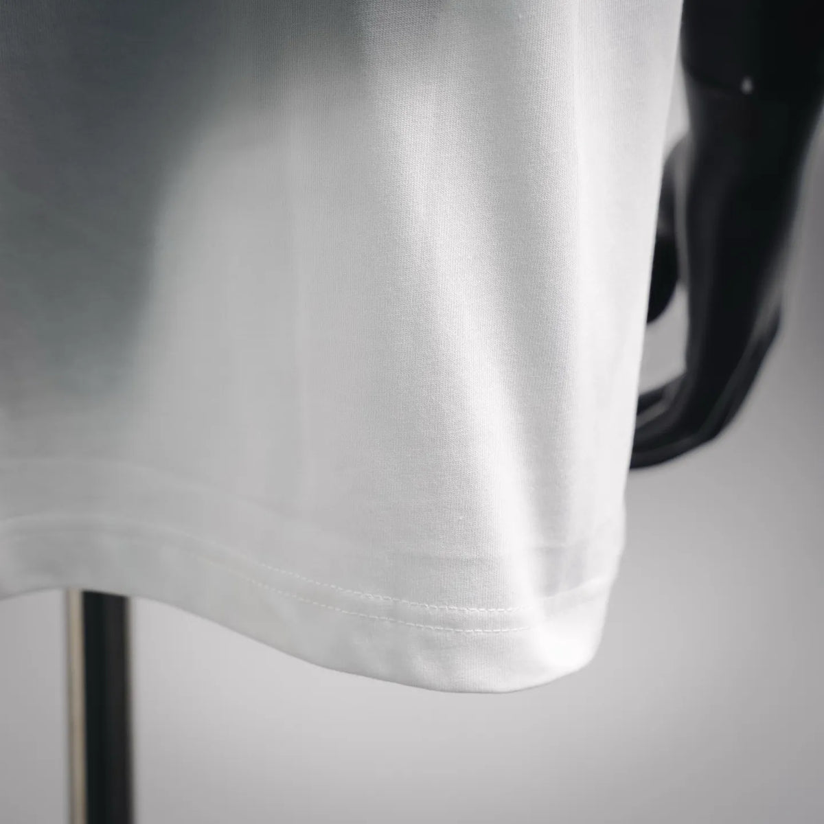 Close-up of white Moncler short-sleeve T-shirt fabric and curved hem.