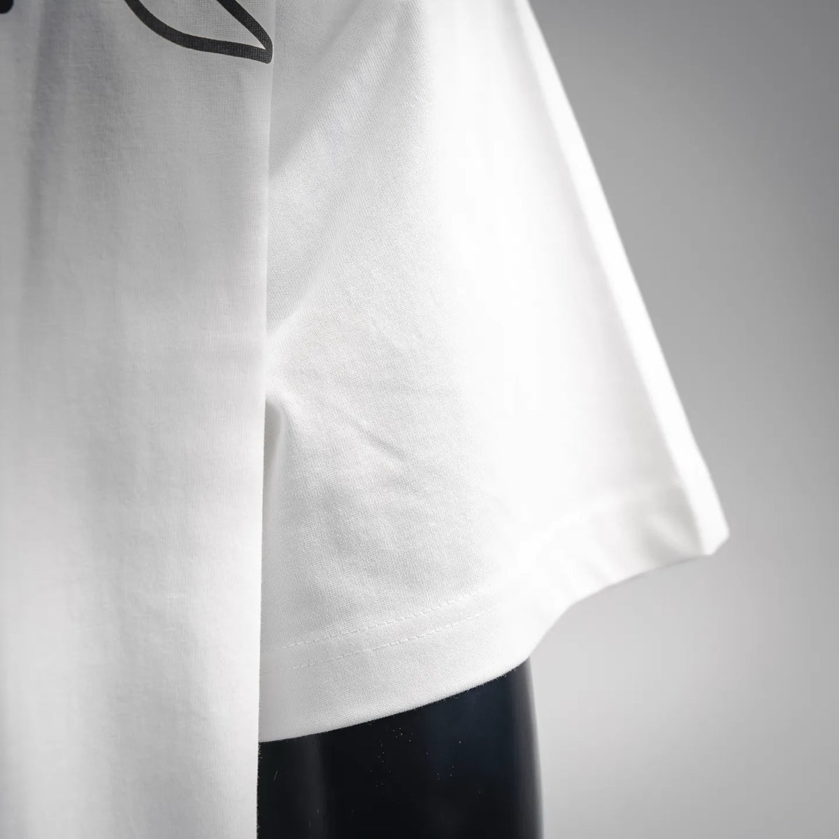 Close-up of white Moncler short-sleeve T-shirt sleeve hem and stitching.