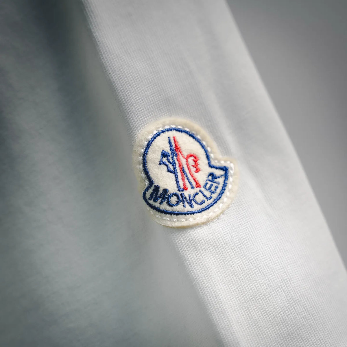 White T-shirt sleeve patch with blue and red logo embroidery