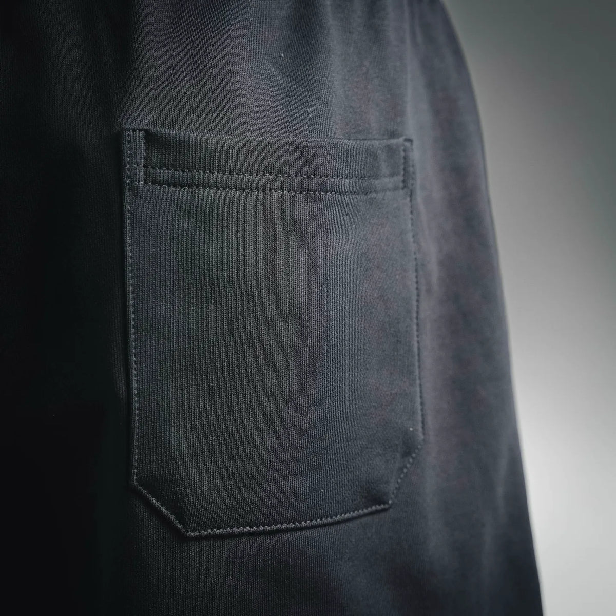Dark shorts with side pocket, visible stitching and textured fabric