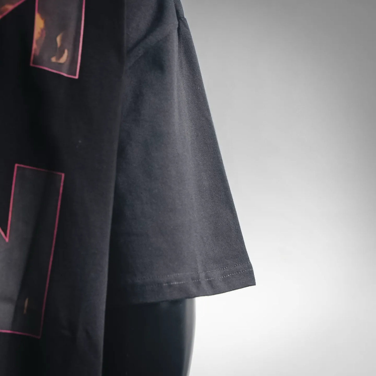 Black short-sleeve T-shirt with side seam and partial pink graphic print