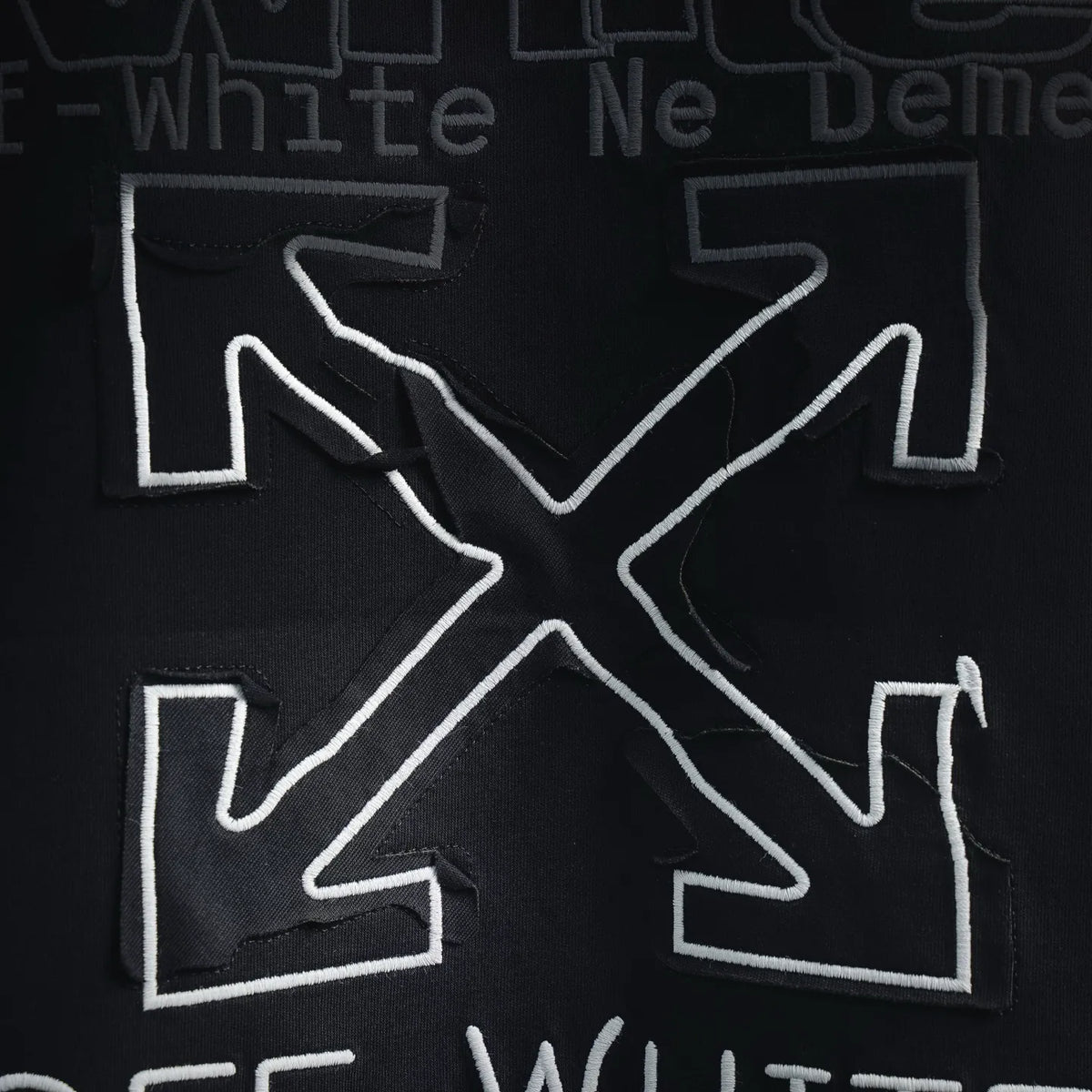 Off-White embroidered-style back logo with white outline on dark shirt