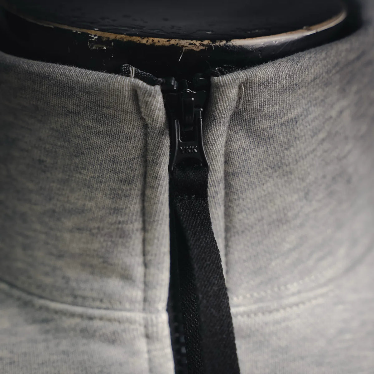 Black zipper and stand collar hardware on light gray sweatshirt