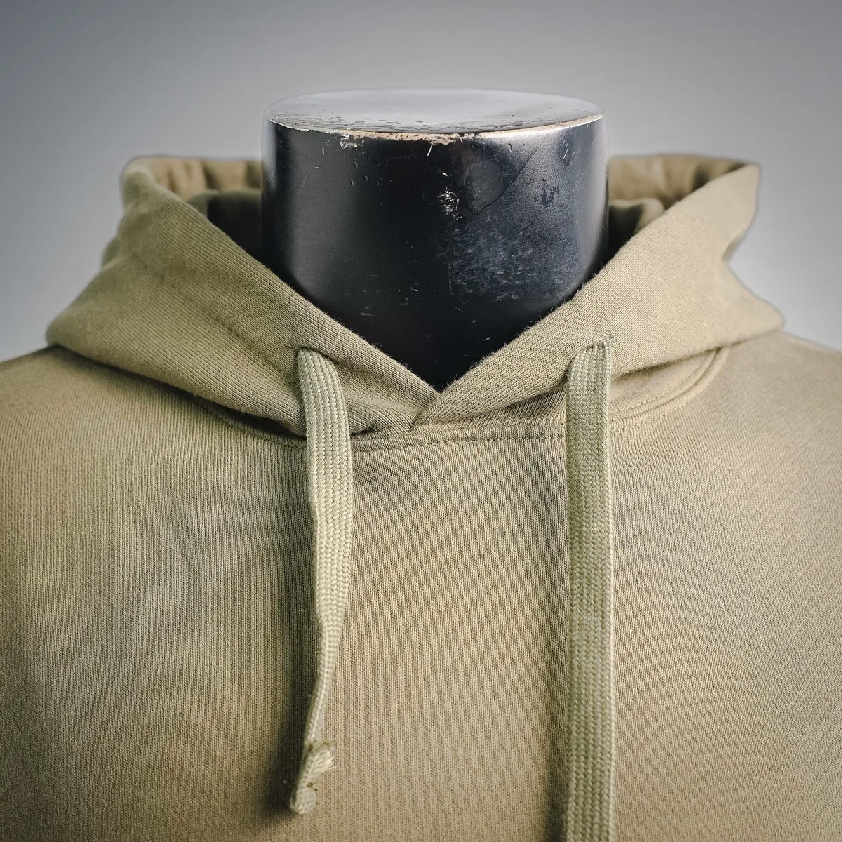 Olive hoodie hood close-up with light drawstrings and neckline seam