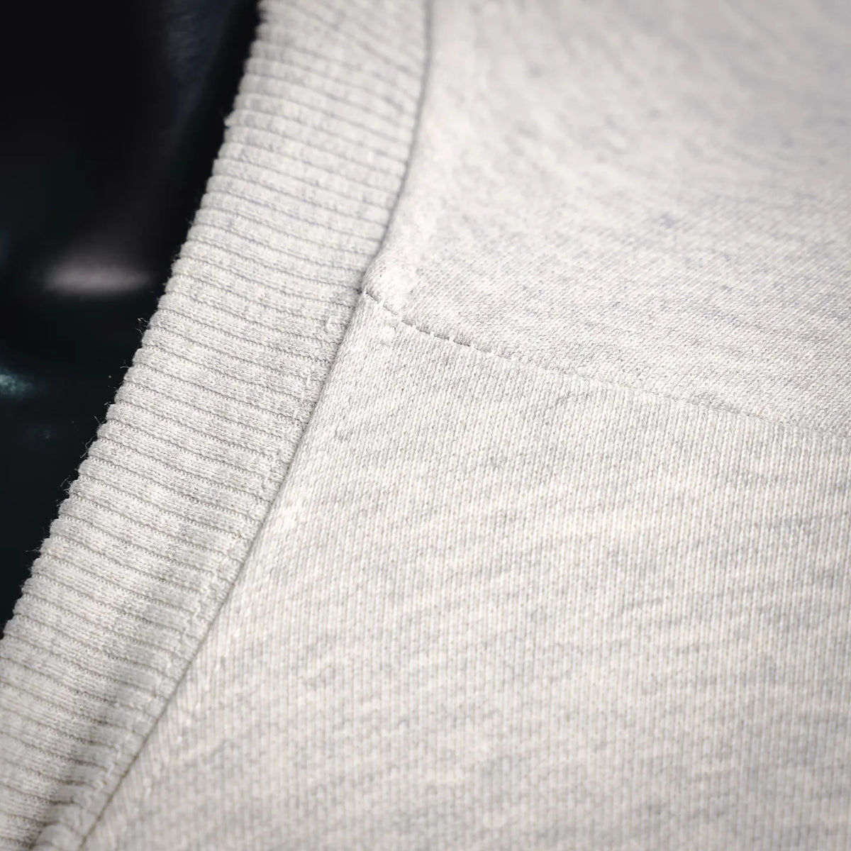 Close-up of light gray sweatshirt fabric with ribbed knit collar trim
