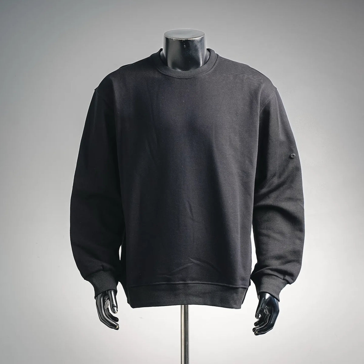 Dark crewneck sweatshirt with long sleeves, ribbed cuffs, and straight hem.