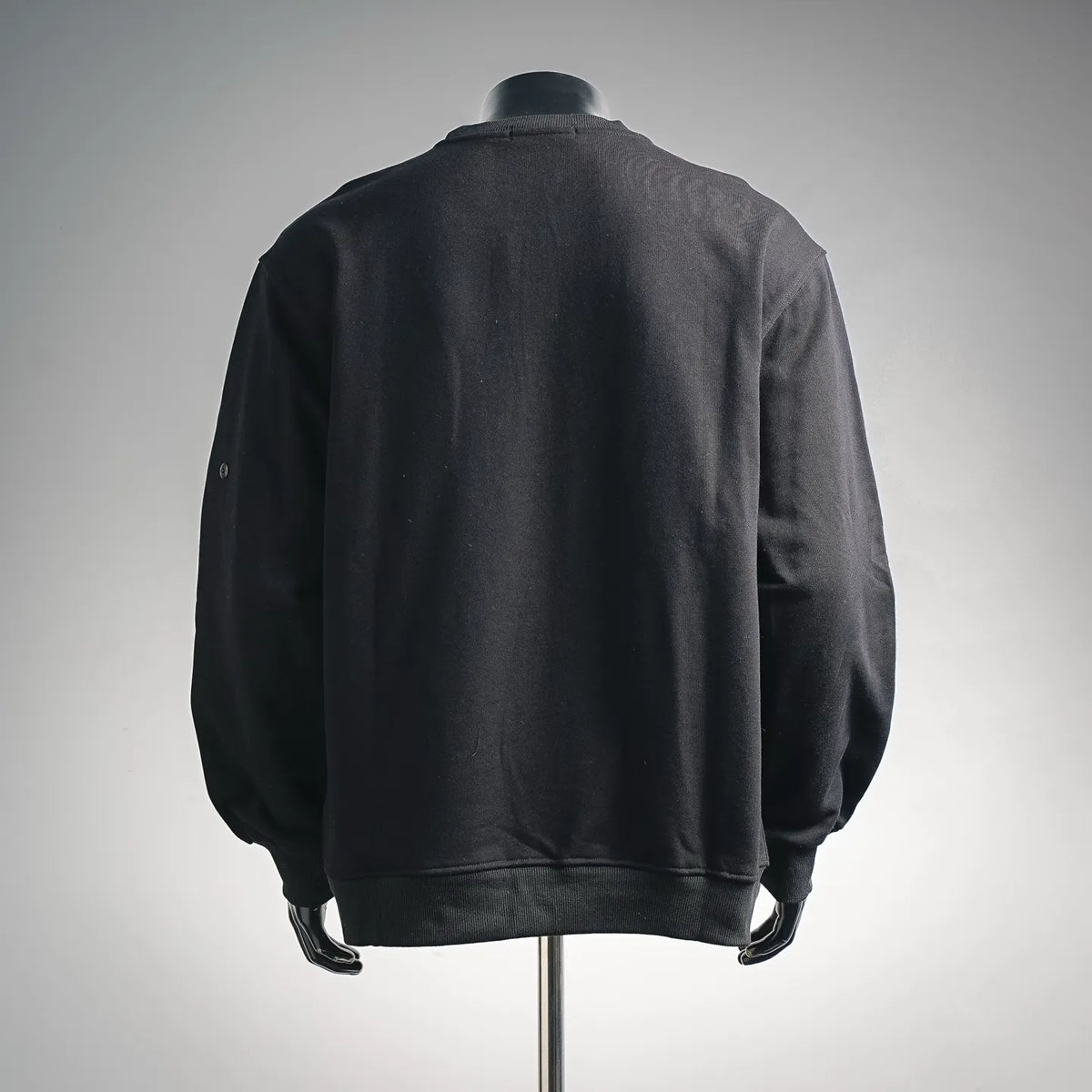 Back view of dark crewneck sweatshirt with ribbed hem and long sleeves.