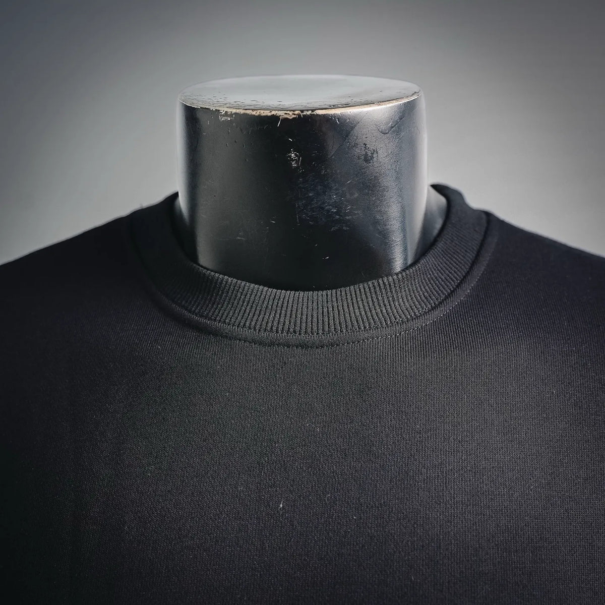 Dark crewneck sweatshirt collar with ribbed knit and subtle fabric texture.