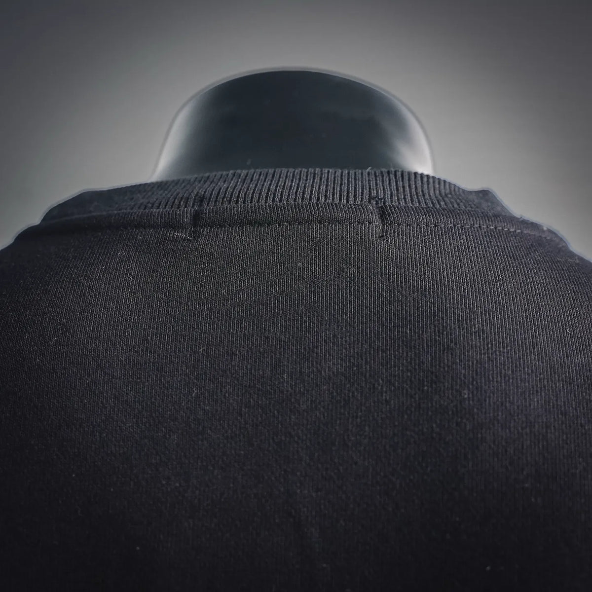 Dark sweatshirt neckline with ribbed collar; close-up on upper back fabric.