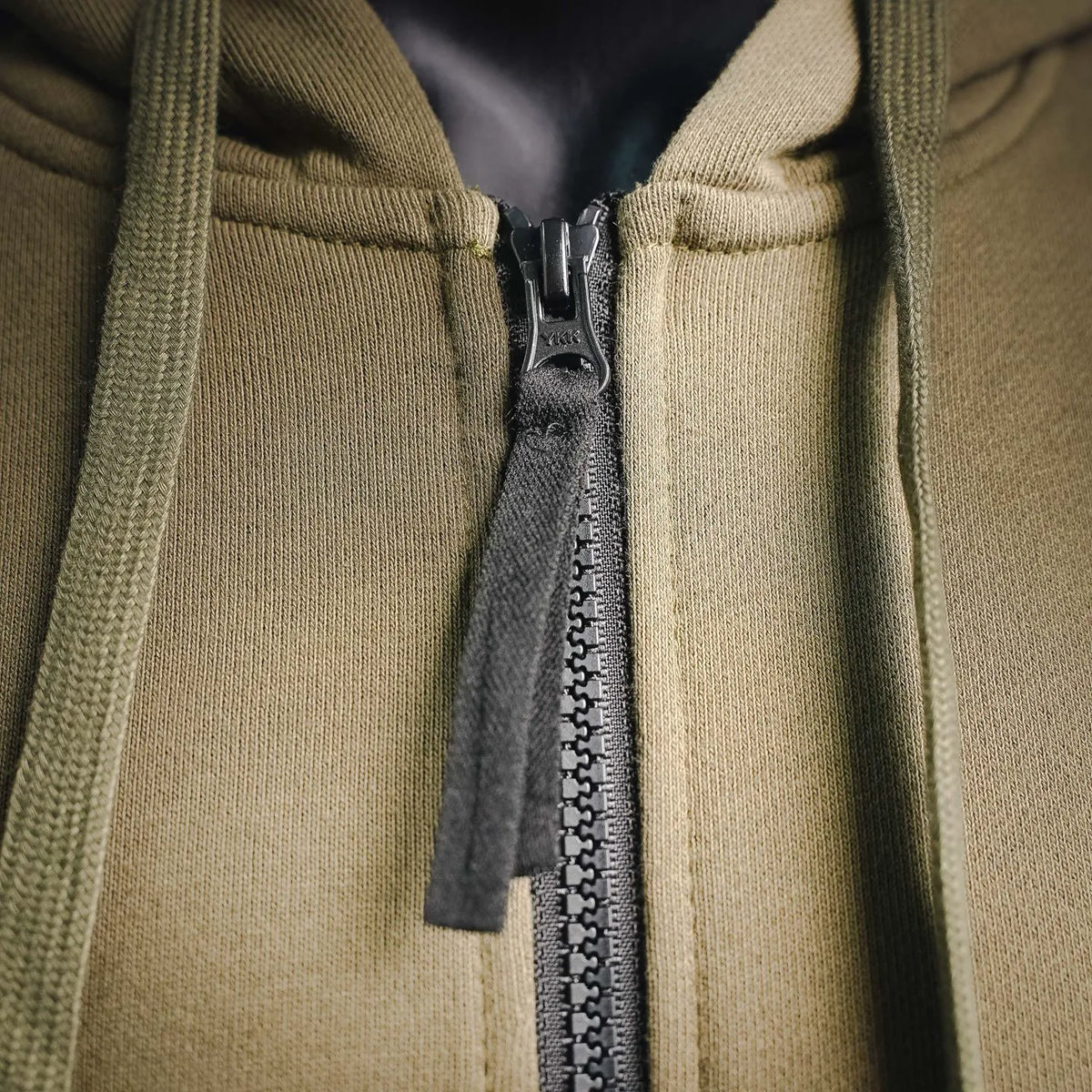 Olive zip-front hooded coat with black zipper and ribbed inner placket
