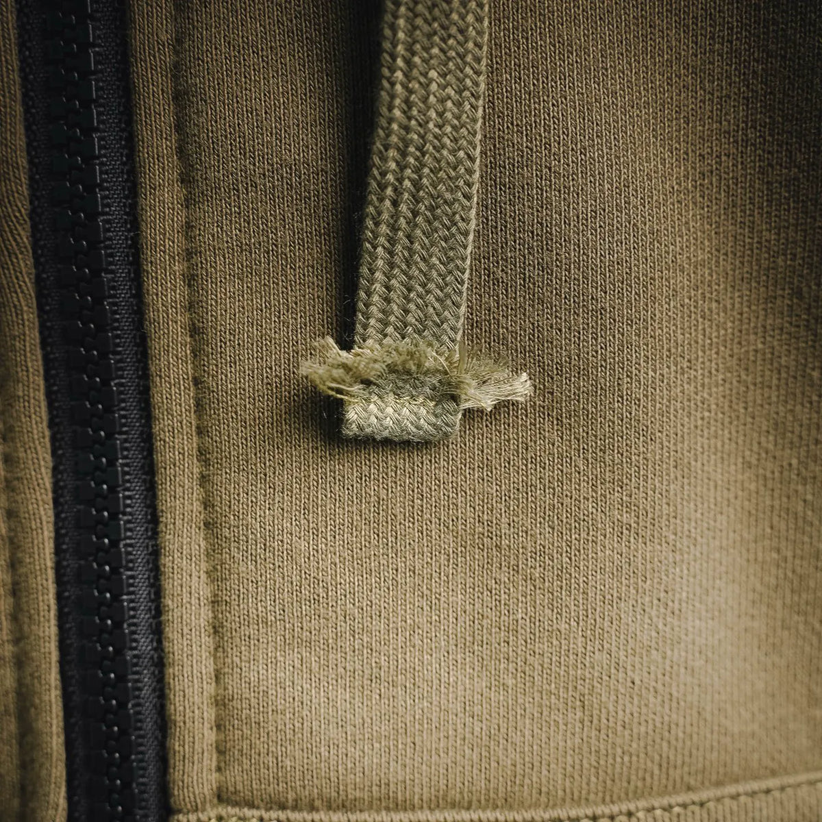 Olive hooded coat chest detail with black zipper and stitched panel