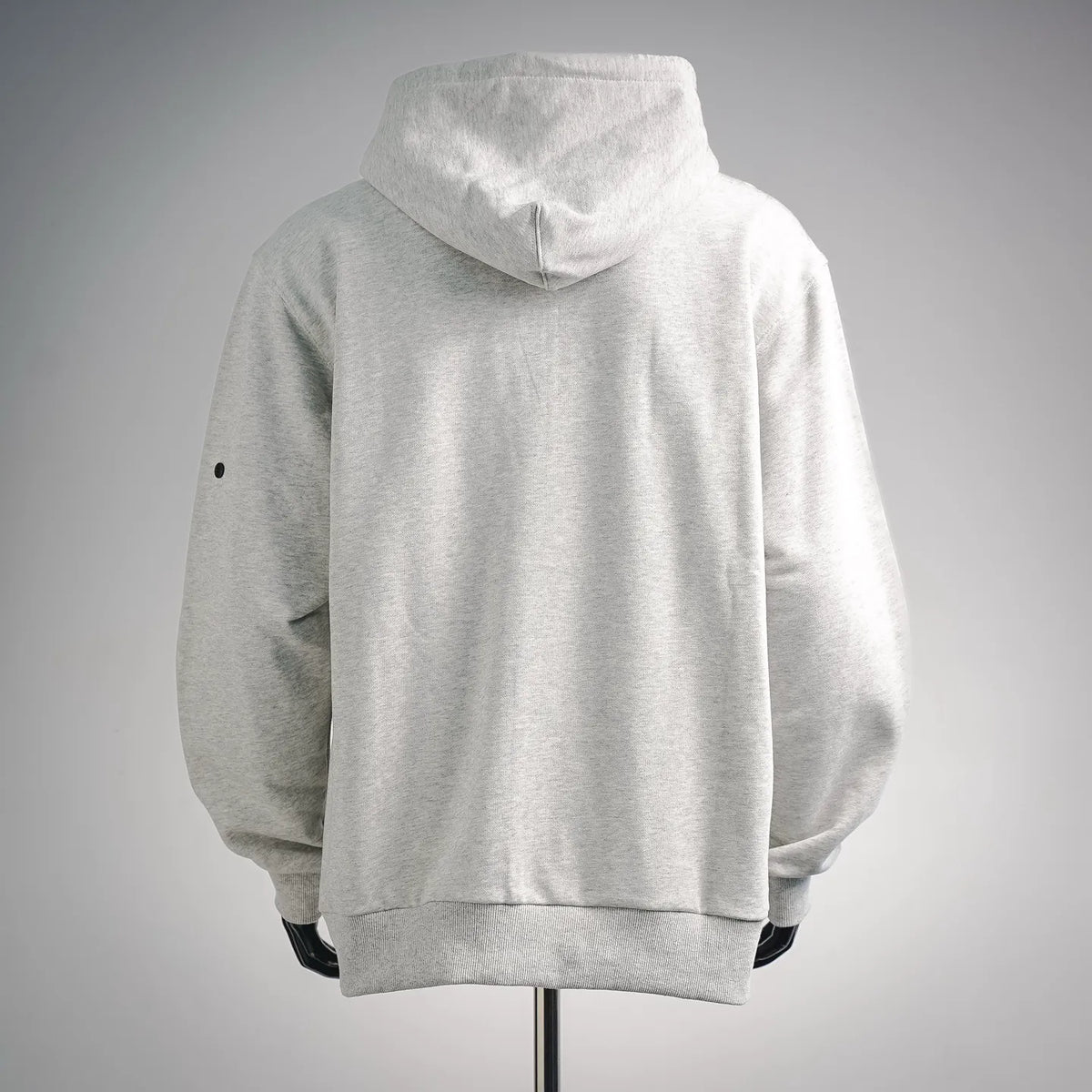 Light gray zip hoodie with raised hood and side seam patch detail; ribbed cuffs