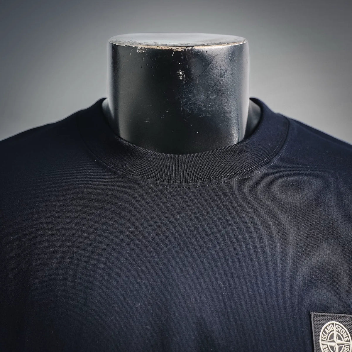 Navy crewneck sweatshirt neckline with ribbed collar detail and left chest badge