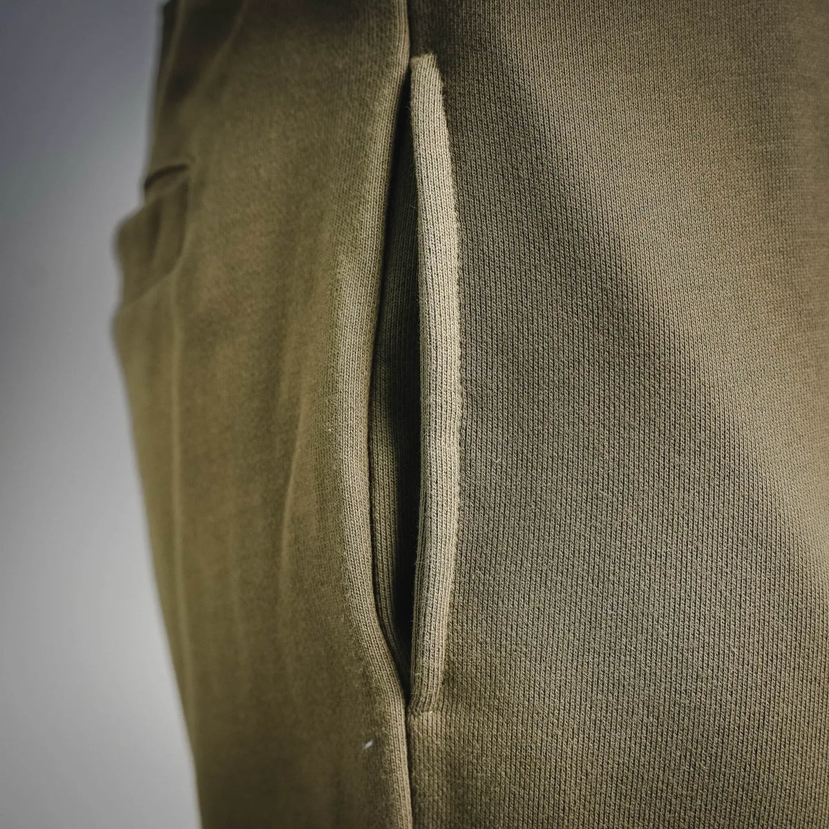 Olive jogger pants close-up of side seam and pocket opening