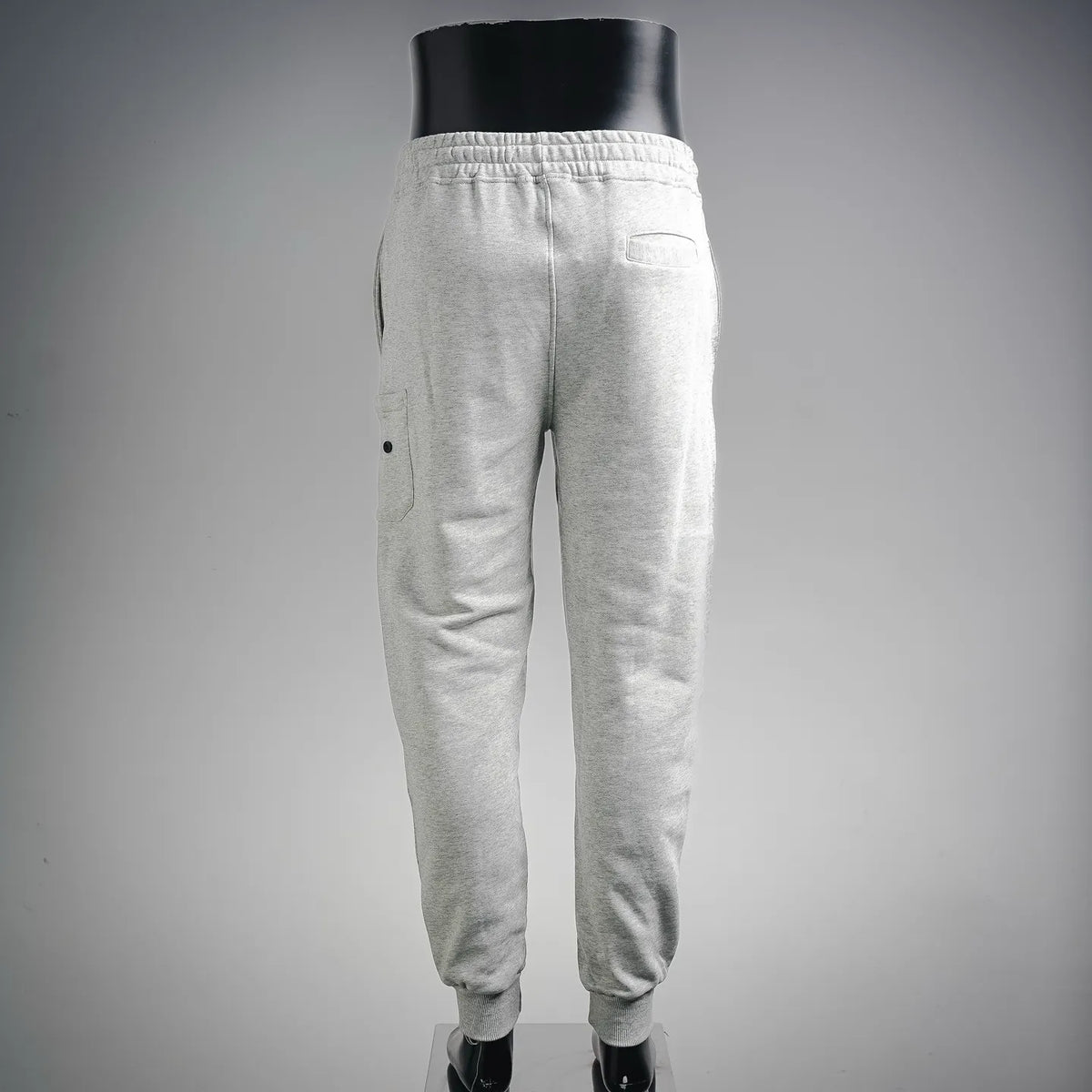 Light gray Stone Island jogger pants, back view with elastic cuffs.