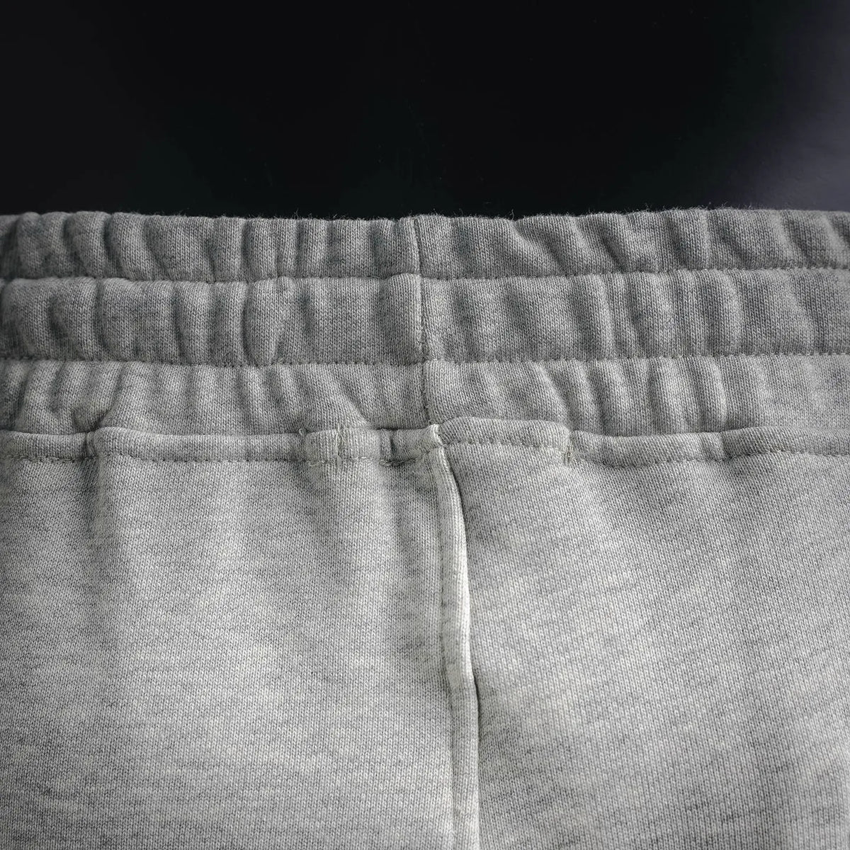 Light gray jogger pants front with elastic waistband and vertical seam.