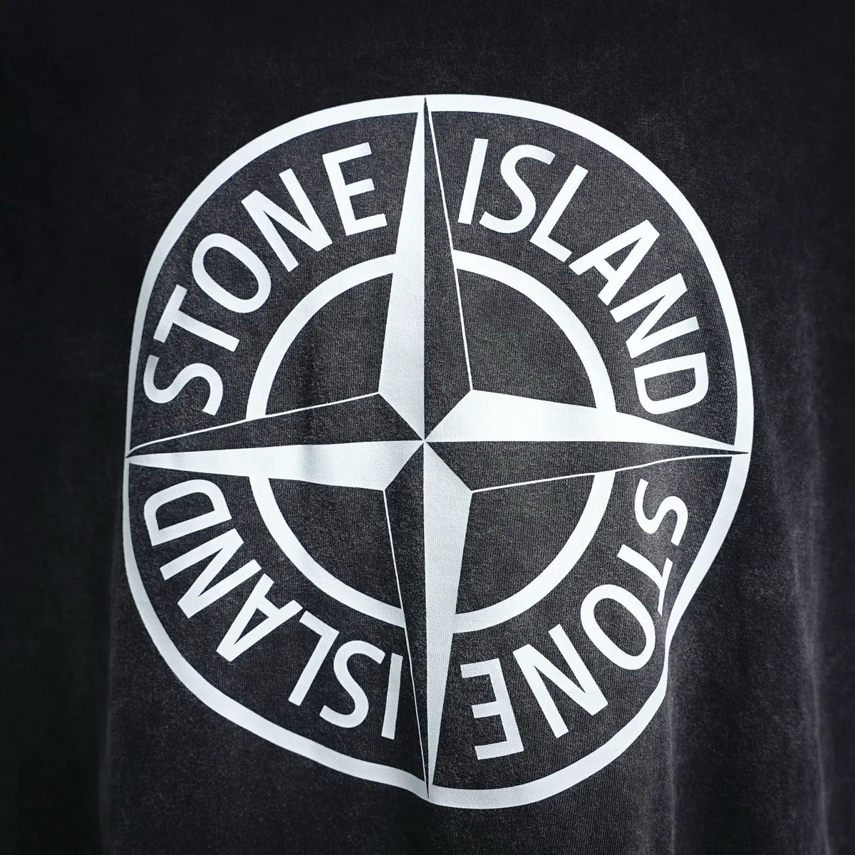 Stone Island circular star logo print on black T-shirt, close-up