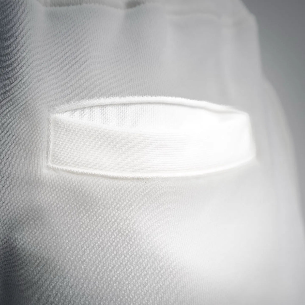 White shorts with textured fabric panel and stitched rectangular patch detail