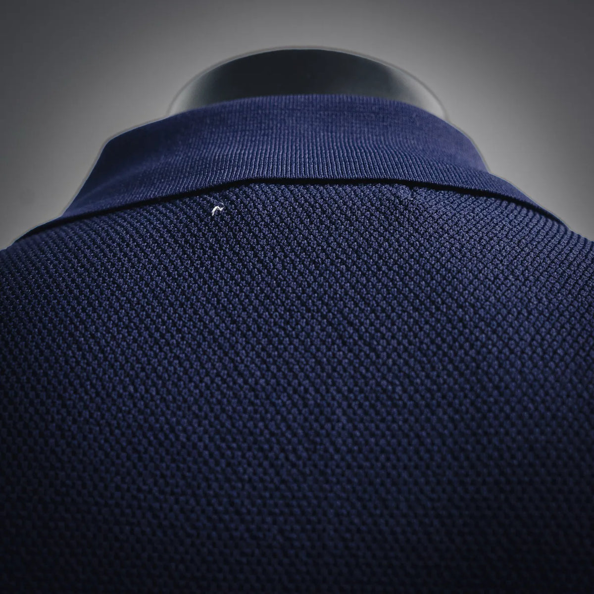 Navy polo knit fabric with ribbed collar edge, close-up texture detail