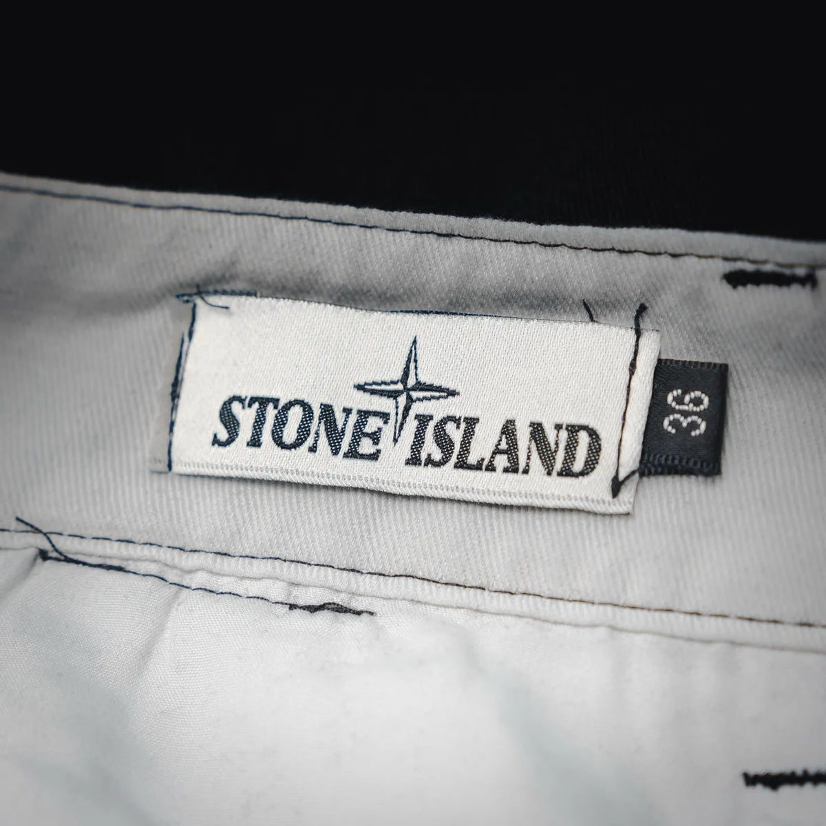 Stone Island pants label on light gray waistband, size tag visible