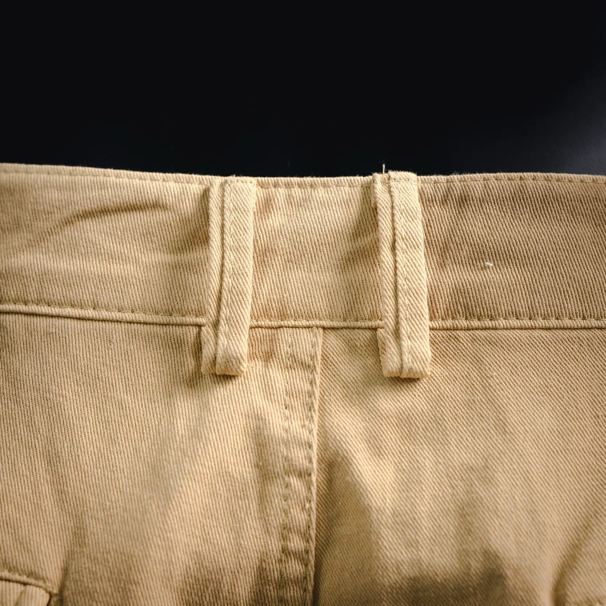 Tan pants waistband with belt loops and stitched front placket