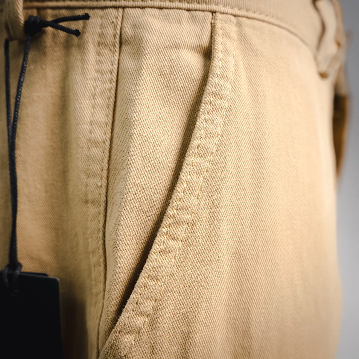 Tan pants side pocket opening with seam lines and stitching