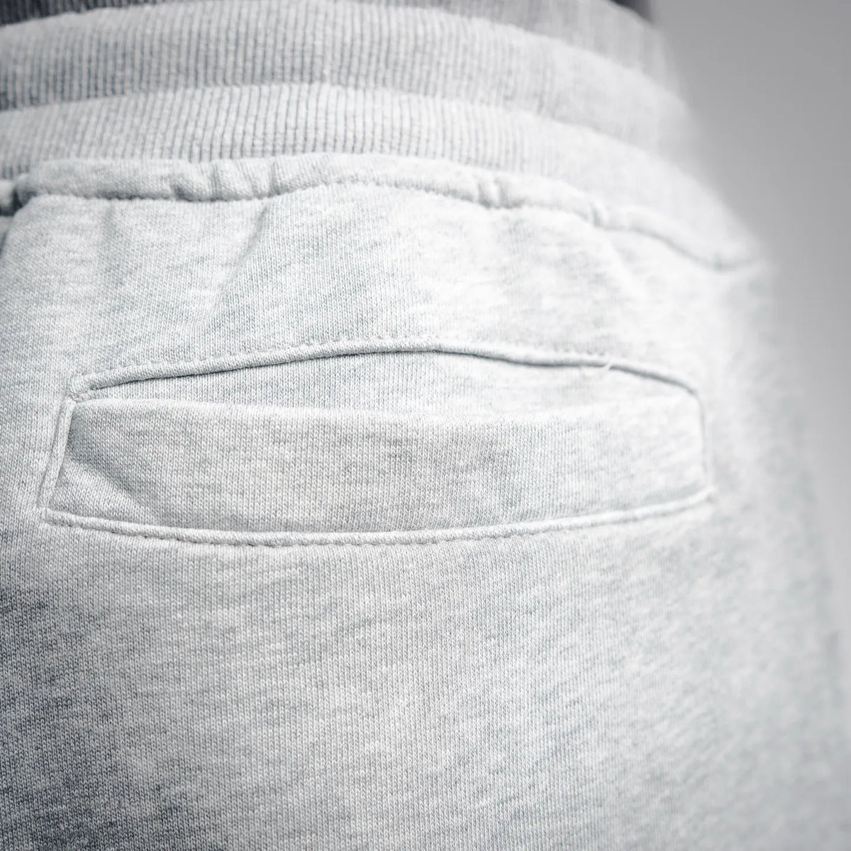Light gray pants front pocket detail with stitched edges and fabric texture