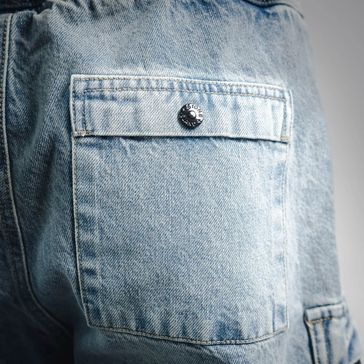 Light blue denim cargo pocket with stitched flap and round button