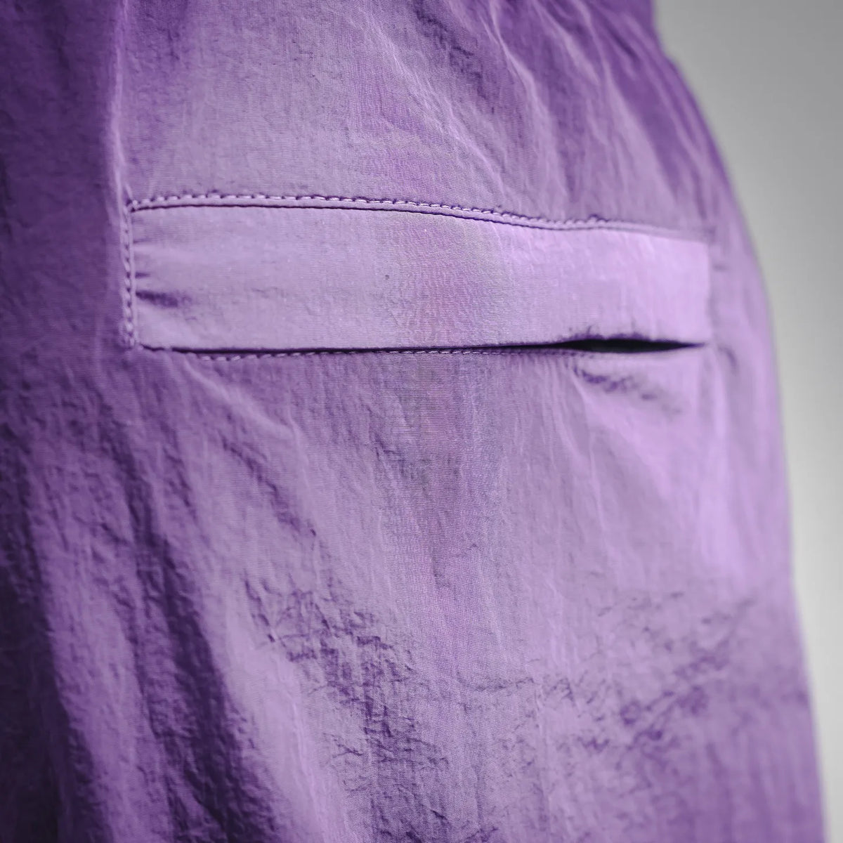 Purple Stone Island shorts back pocket area with contrast stitched seam.