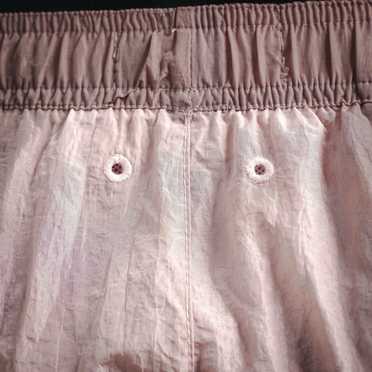 Light pink shorts detail: elastic waist, buttons, and center front seam
